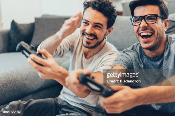 amigos muy contentos de jugar video juegos - jugar fotografías e imágenes de stock