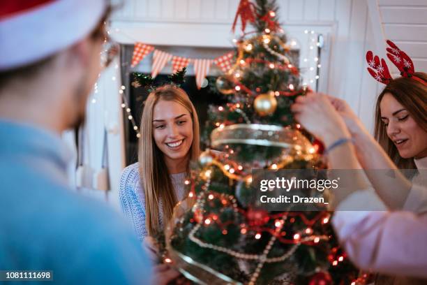 christmas party - generation z is celebrating christmas and new year and having fun together - decorating christmas tree stock pictures, royalty-free photos & images