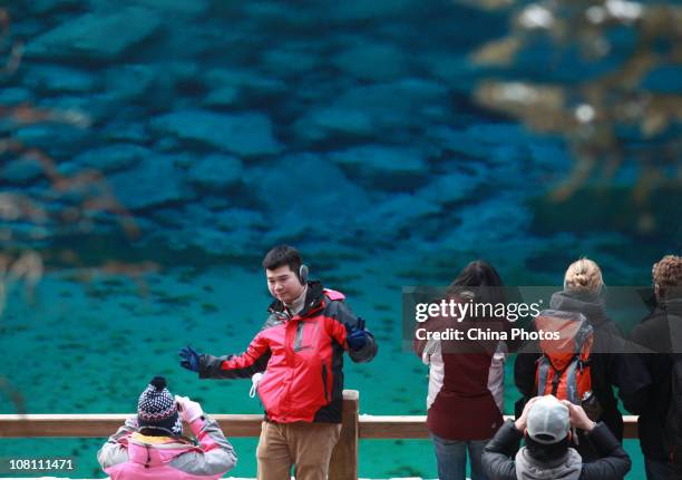 Tourists pose for a photo in front of the Five Color Lake at the Jiuzhaigou Scenic Spot on January 18, 2011 in Jiuzhaigou County of Aba Tibetan and...