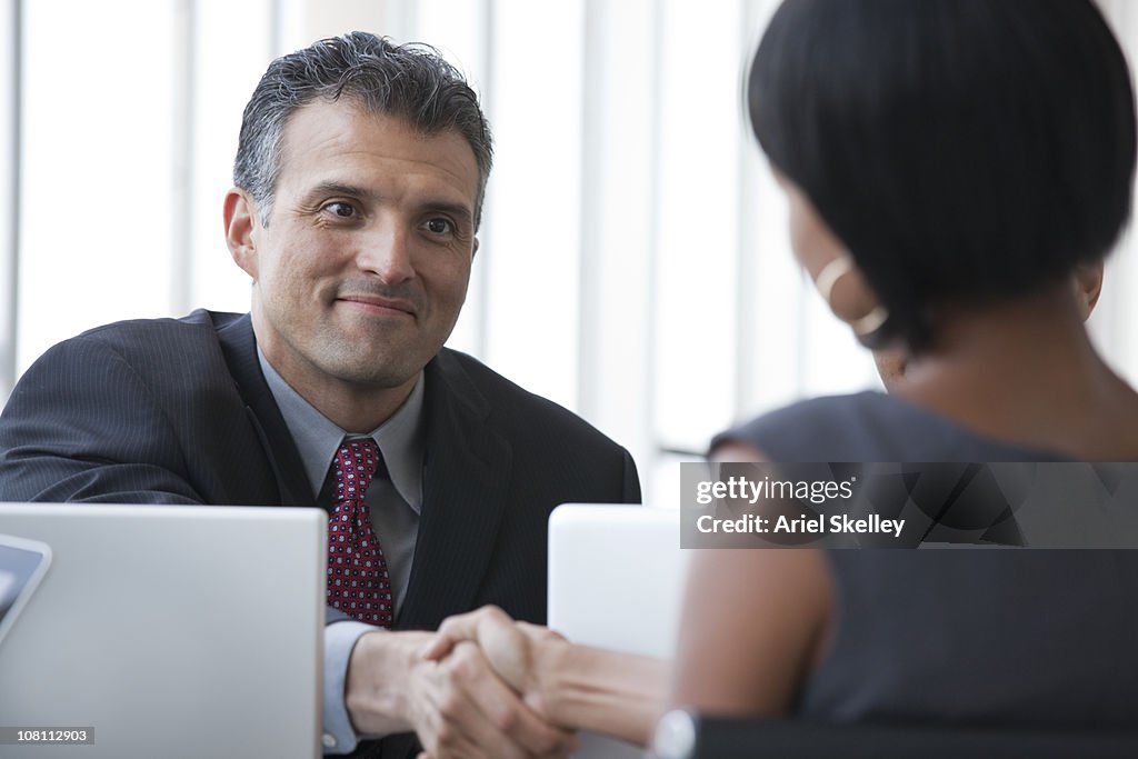 Smiling business people shaking hands in meeting