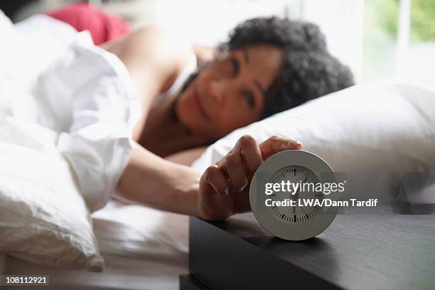 black woman turning of alarm clock - awake day stockfoto's en -beelden