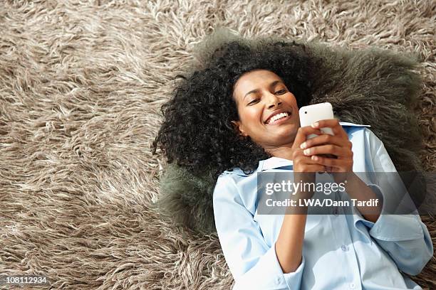 black woman laying on floor using cell phone - shag rug stock pictures, royalty-free photos & images