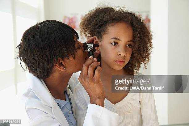 doctor examining girl's ear with otoscope - otoscope stockfoto's en -beelden