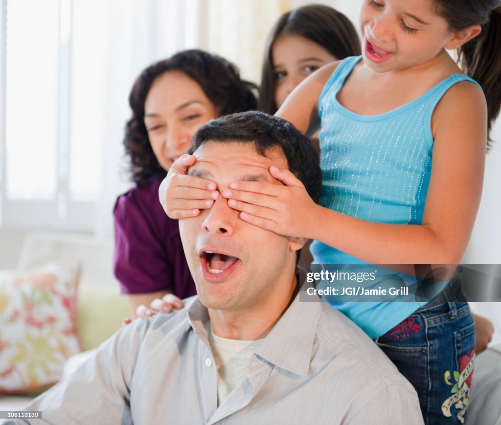 Daughter covering surprised father's eyes