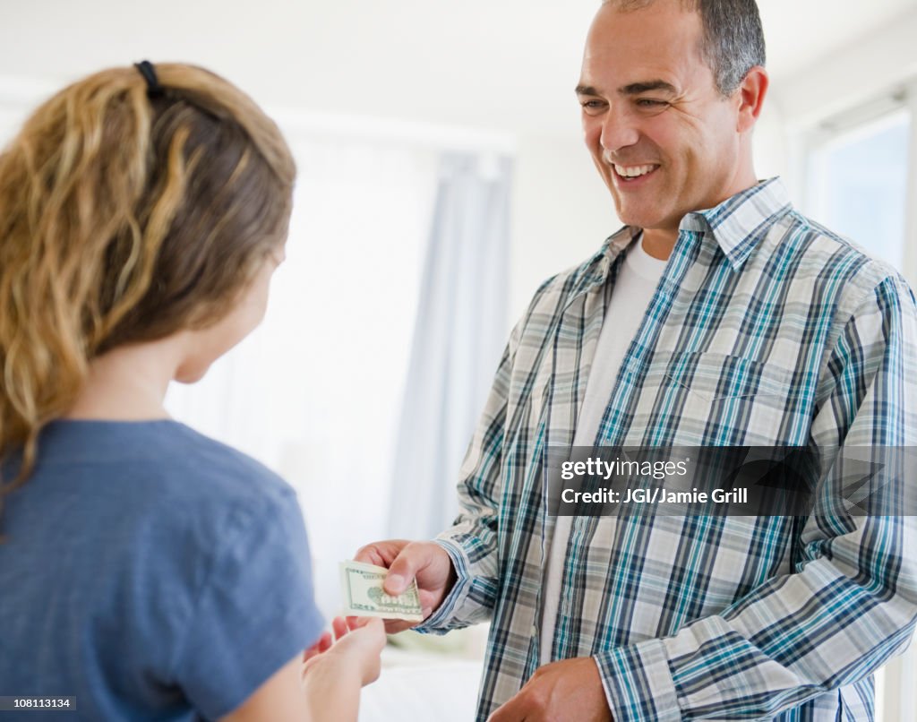 Hispanic father handing daughter money