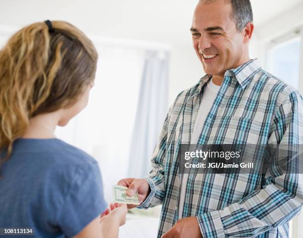 hispanic father handing daughter money - money borrow stockfoto's en -beelden