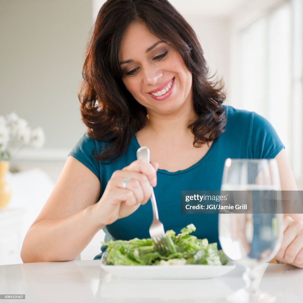 Smiling Hispanic woman eating salad for lunch