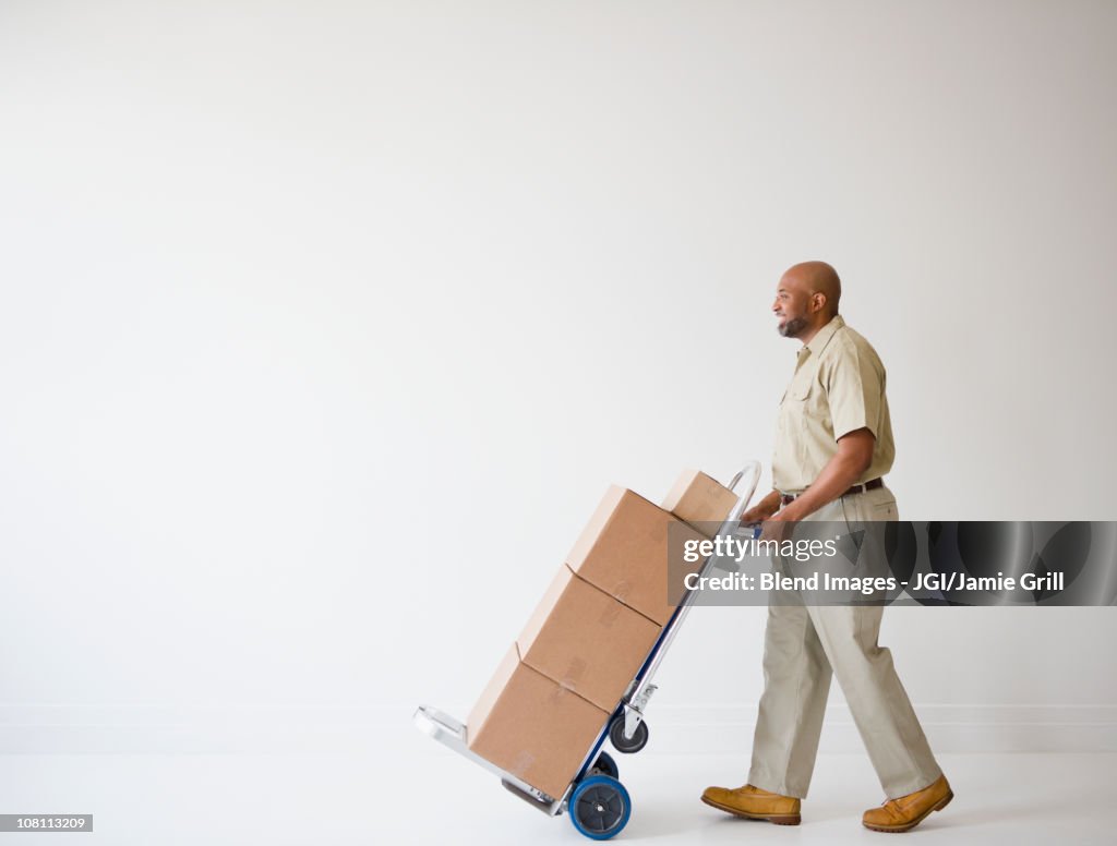 African American deliveryman pushing hand truck with boxes