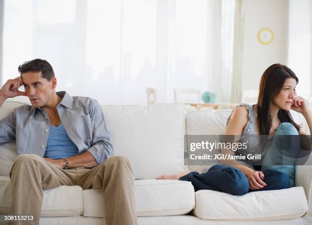 angry mixed race couple having argument on sofa - couple ignore stock-fotos und bilder