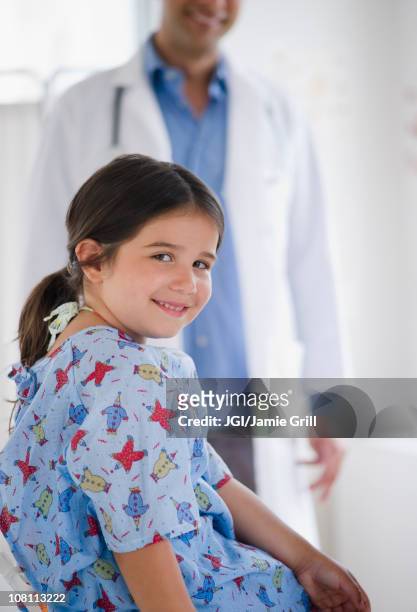 smiling mixed race girl in examination room with doctor in background - two young arabic children only indoor portrait stock pictures, royalty-free photos & images
