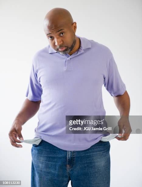 sad african american holding out empty pockets - empty pockets stock pictures, royalty-free photos & images