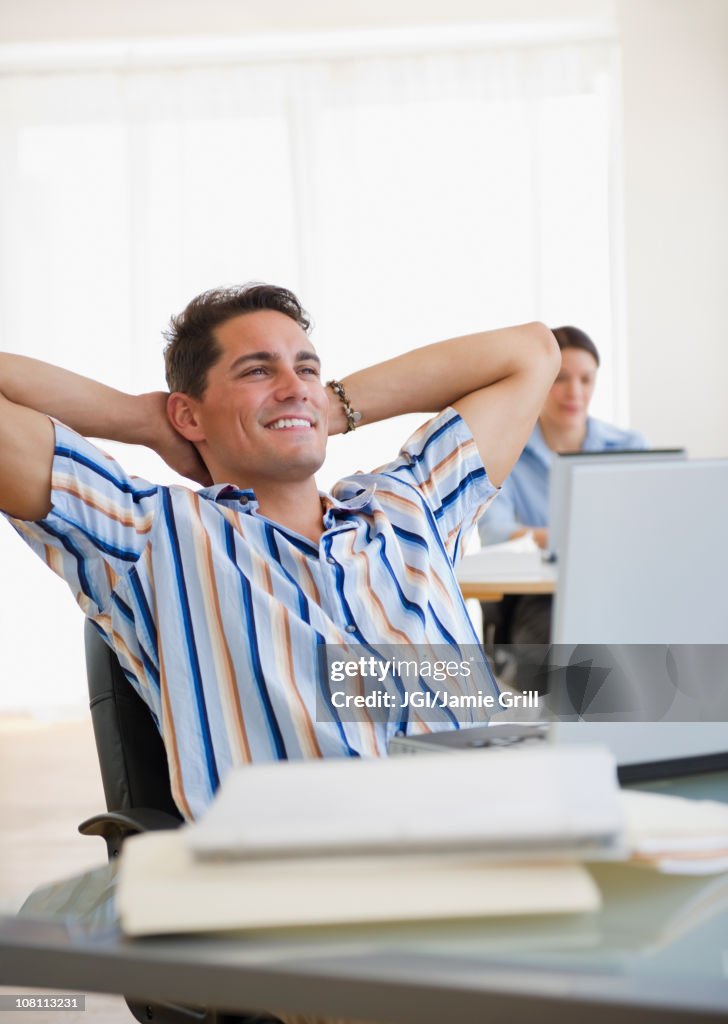 Mixed race businessman leaning back in chair at desk