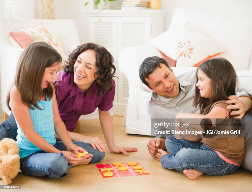 Father and mother playing game in livingroom with children