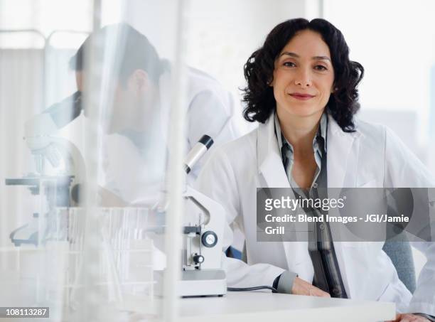 hispanic researcher in laboratory next to microscope - female scientist ストックフォトと画像