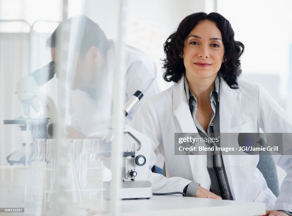 Hispanic researcher in laboratory next to microscope