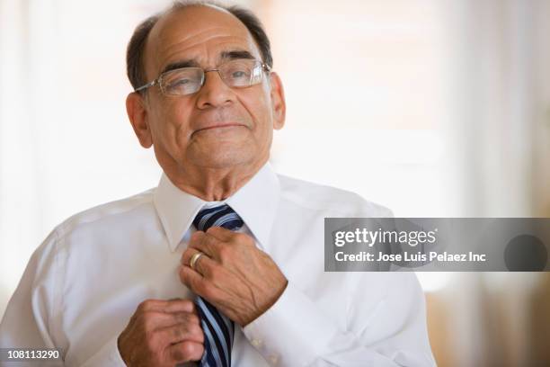 senior hispanic man adjusting necktie - desamarrado imagens e fotografias de stock
