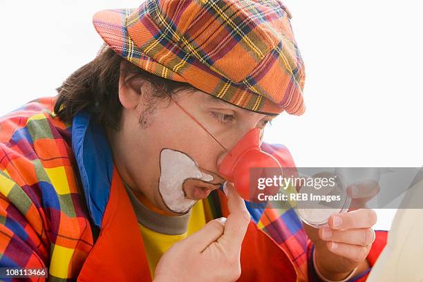 hispanic man putting on clown makeup - clown's nose stock pictures, royalty-free photos & images