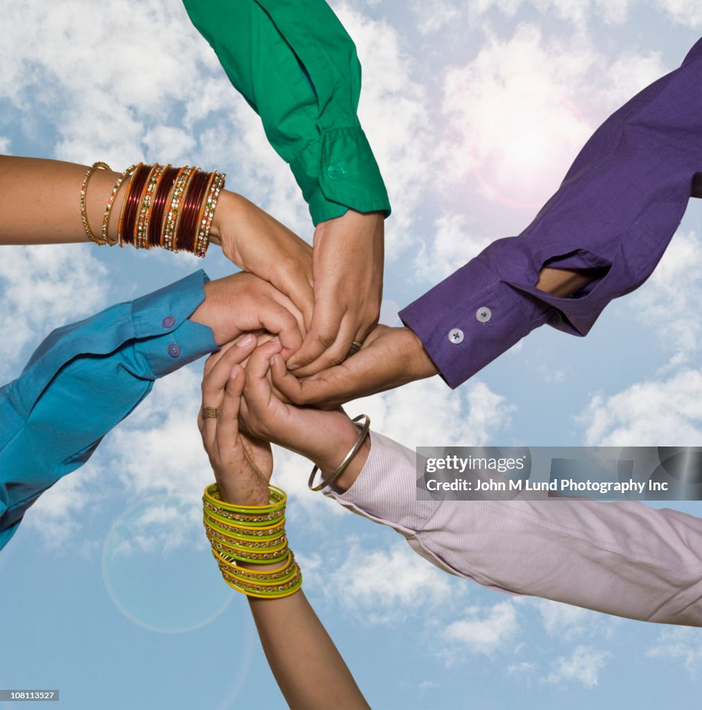 People holding hands together against blue sky