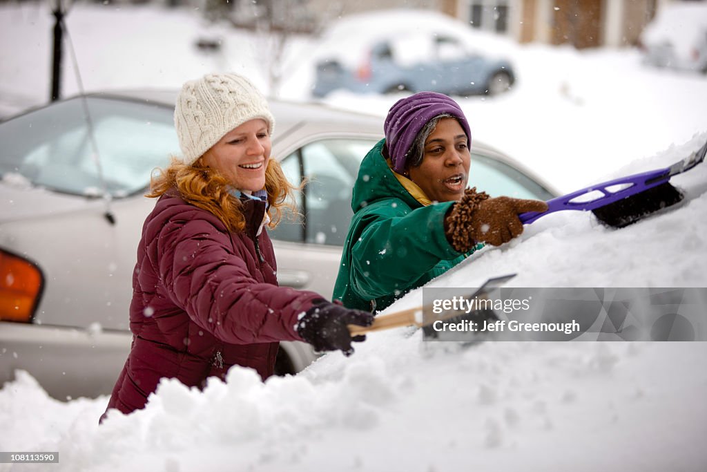 Deux femmes Racler neige de pare-brise