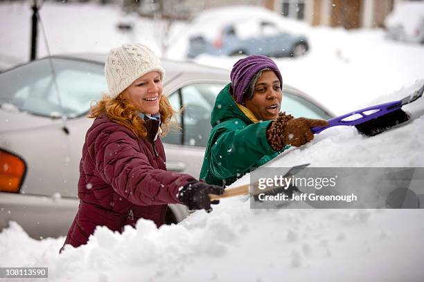 two women scraping snow from windshield - winter car window stock pictures, royalty-free photos & images