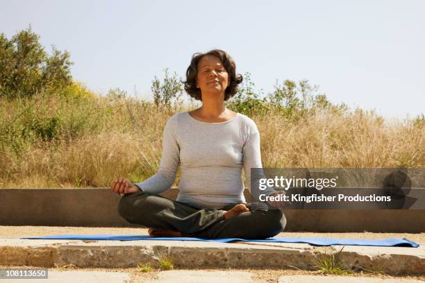 mixed race woman practicing yoga outdoors - lotus position stock pictures, royalty-free photos & images