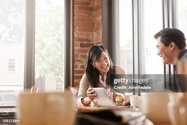 chinesische frau und mann mit digitalen tablet im café - enjoying coffee cafe morning light stock-fotos und bilder