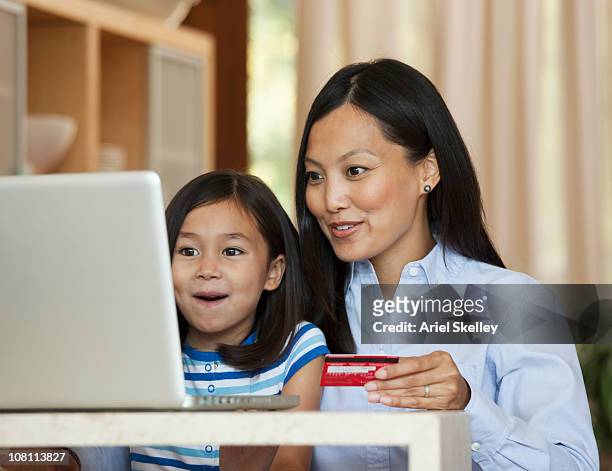 mother and daughter using credit card online - filipino girl stockfoto's en -beelden