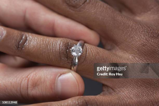 close up of man putting engagement ring on girlfriend - black women engagement rings foto e immagini stock
