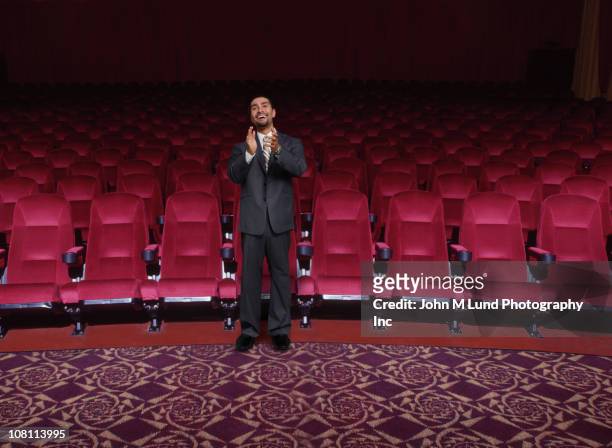 hispanic businessman clapping in empty theater - ovación de pie fotografías e imágenes de stock