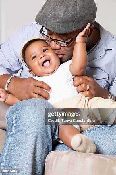 african american holding and kissing baby son in lap - tickling 個照片及圖片檔