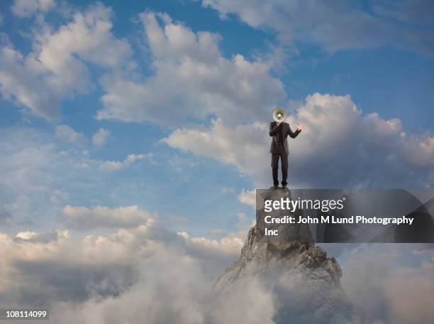 caucasian businessman using bullhorn on mountain top - preacher stock pictures, royalty-free photos & images