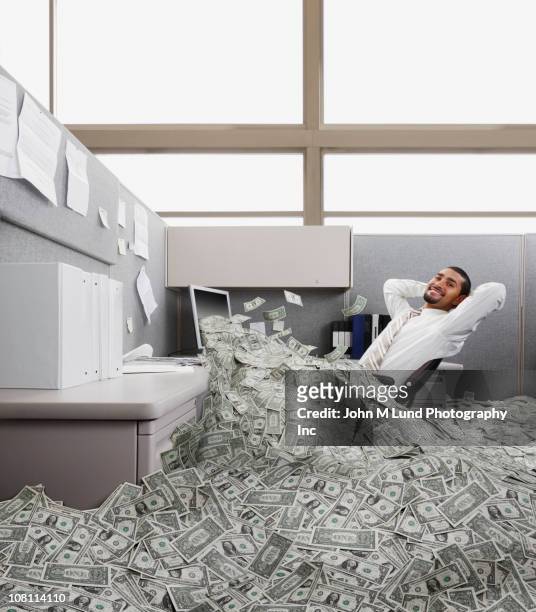 hispanic businessman in cubicle covered in one dollar bills - millionnaire stock pictures, royalty-free photos & images