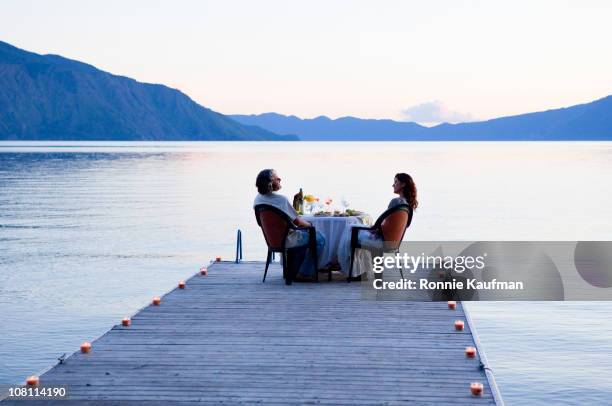 caucasian couple having dinner on pier at lake - elegant couple stockfoto's en -beelden