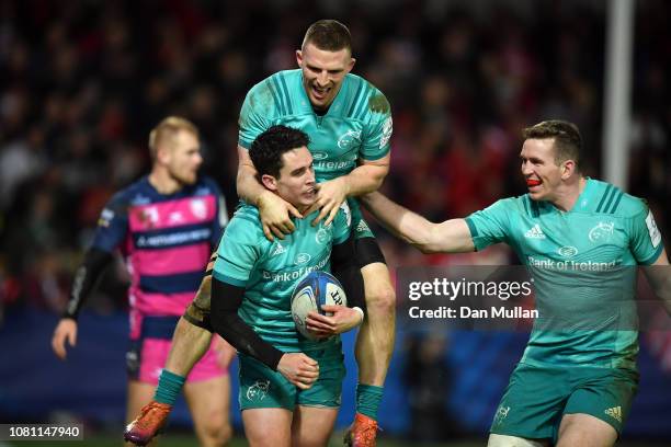 Joey Carbery of Munster celebrates with team mates Andrew Conway and Chris Farrell after scoring a try during the Champions Cup match between...