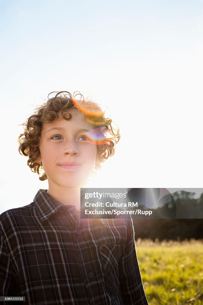 Boy standing in meadow by sunset