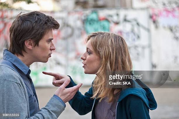 young couple arguing in street - couple pointing imagens e fotografias de stock