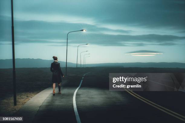 woman and the ufo on the rural road at dusk - kidnapping imagens e fotografias de stock
