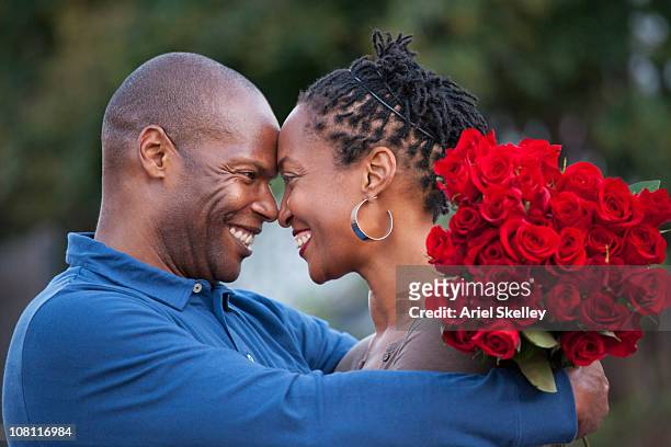 hombre negro, que abrazan esposa y dando a su red roses - black rose fotografías e imágenes de stock