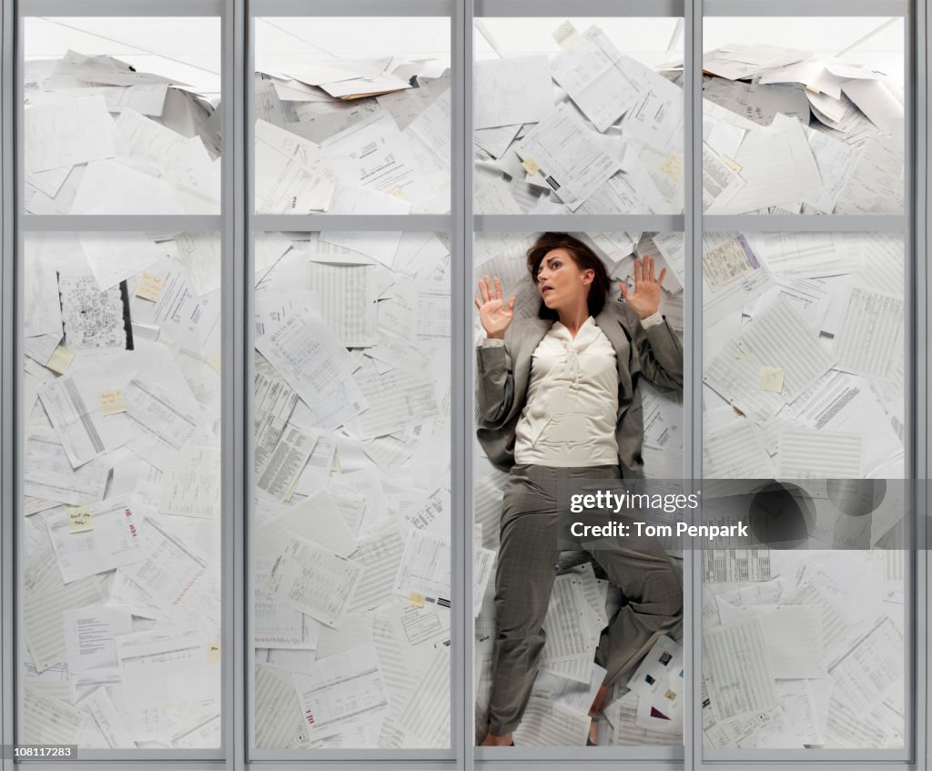 Mixed race businesswoman drowning in paperwork