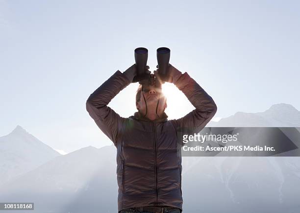 man looks upwards through binoculars, mountains - looking through binoculars stock pictures, royalty-free photos & images
