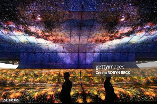 Security guard standing in the "Massive Curve of Nature" display of 250 curved LG OLED televisions is reflected in a mirror on the last day of CES...