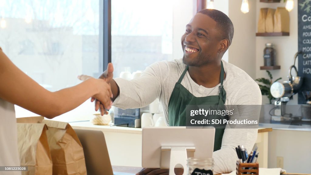 Masculino café barista aperta a mão do cliente