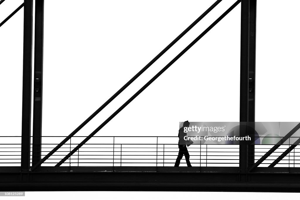 Silhouette of Man Walking Down Walkway