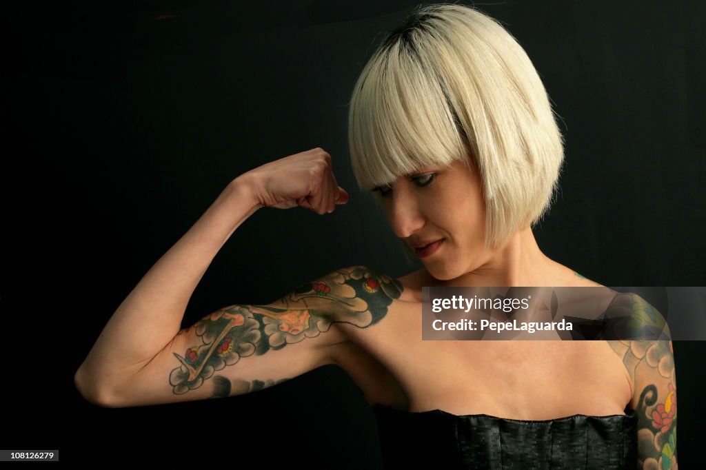 Portrait of Young Woman Flexing Tattooed Arm Muscles