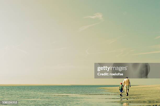 father & son beach scene - distant family stock pictures, royalty-free photos & images