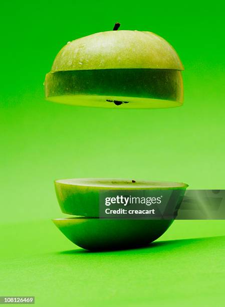 floating, sliced appled on green background - green apple slices stock pictures, royalty-free photos & images