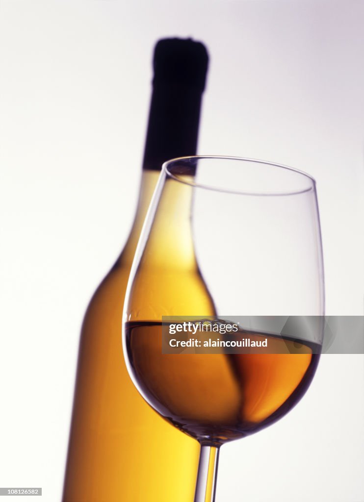 Glass of White Wine with Bottle in Background