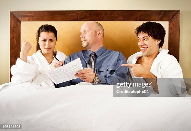 man making woman sign legal papers in bed - three people bed stock pictures, royalty-free photos & images