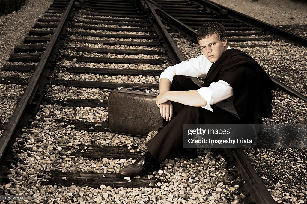 Young Businessman Sitting on Train Tracks