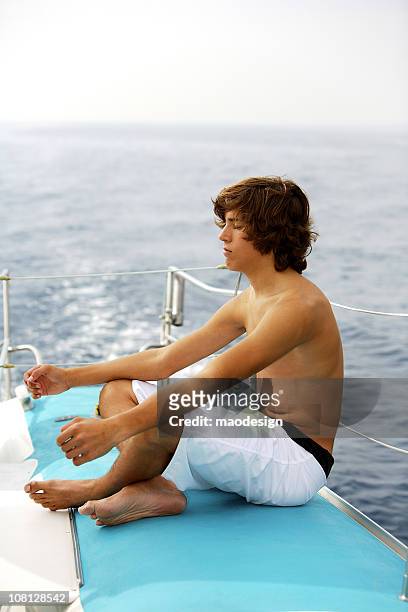 man sitting on boat - teen boy barefoot stock pictures, royalty-free photos & images